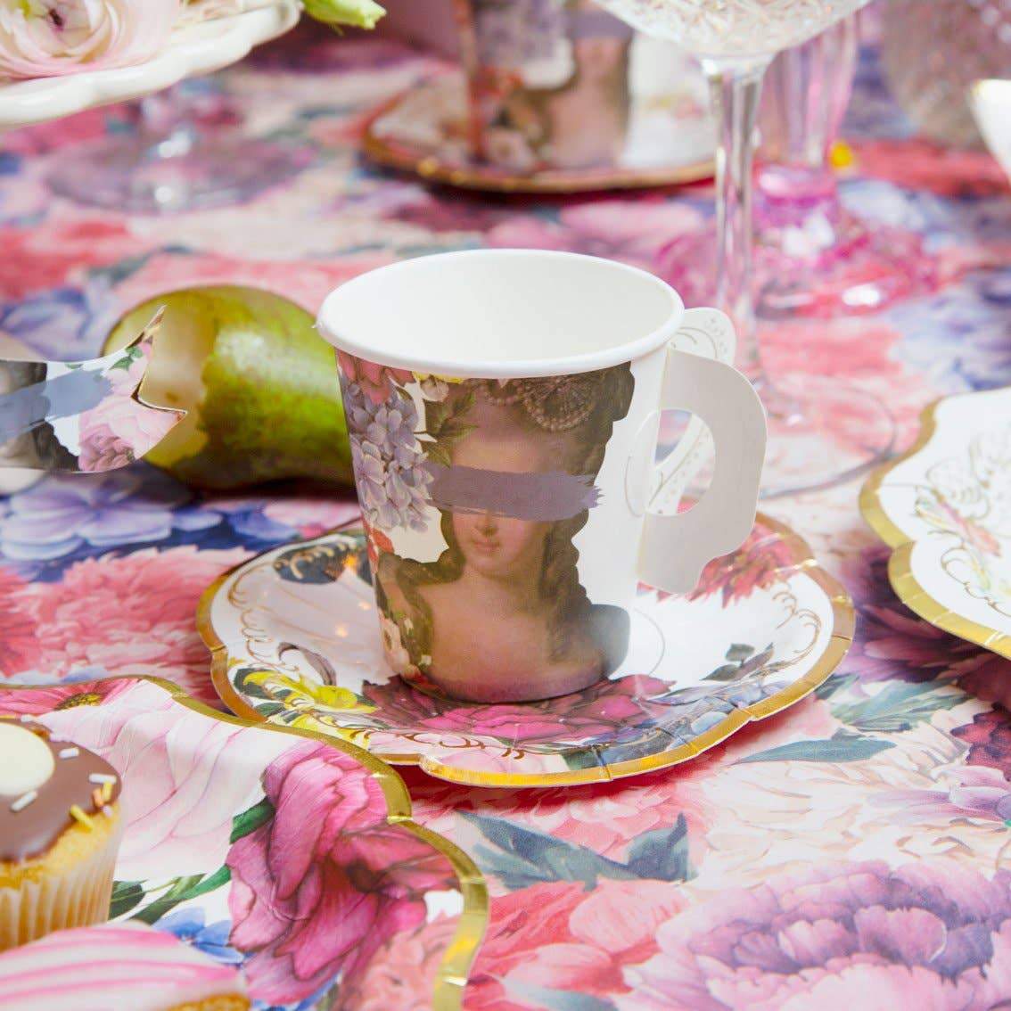 Decoratore vicino al tavolo da festa in colori pastello con tovaglia rosa,  piatti colorati di carta, tazze e posate dorate. decorazione festa di  compleanno ragazza, tappi festivi.